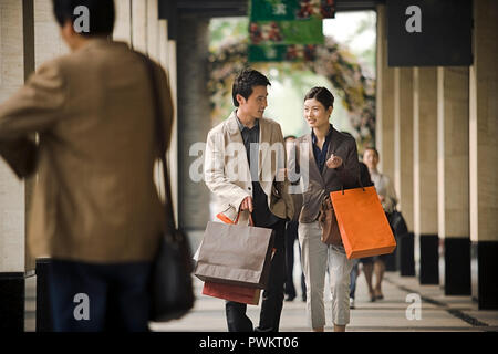 Balades dans les bras de couple carrying shopping bags. Banque D'Images