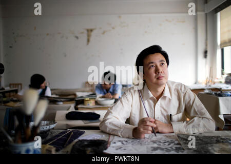 Mid-adult man painting art dans une salle de classe. Banque D'Images