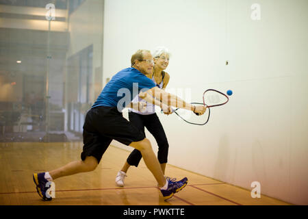 Senior woman et mid-adult man playing squash ensemble dans une cour de jeu. Banque D'Images