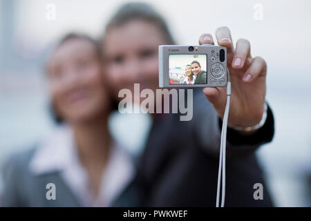 Deux jeunes femmes souriant posant pour une photo sur un appareil photo numérique. Banque D'Images