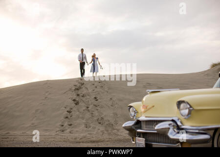 Couple running down sand dune Banque D'Images
