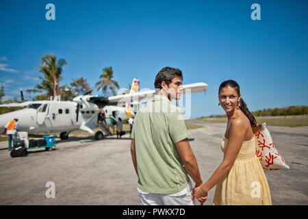 Smiling young couple marche main dans la main vers un avion. Banque D'Images