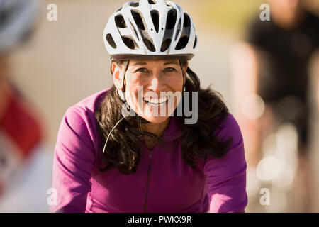 Femme mature portant un casque de vélo et souriant Banque D'Images