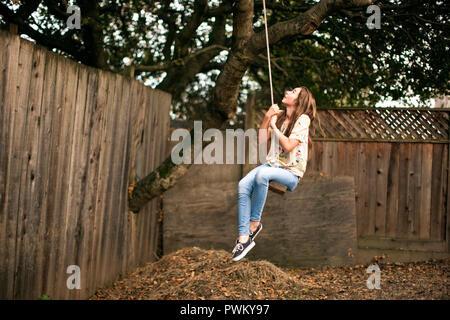 Teenage girl on rope swing en arrière-cour. Banque D'Images