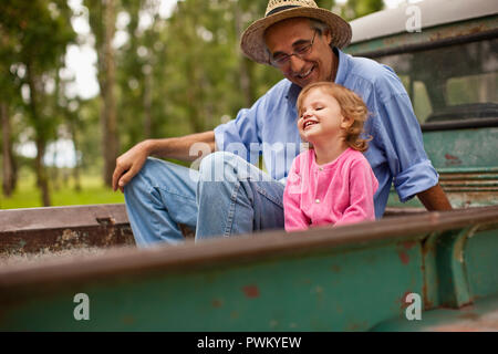 Homme mûr et sa petite-fille enfant mignon assis dans l'arrière de camion. Banque D'Images