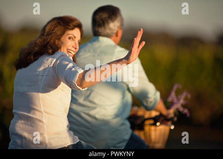 Middle-aged woman having fun riding la location avec son mari dans le vignoble. Banque D'Images
