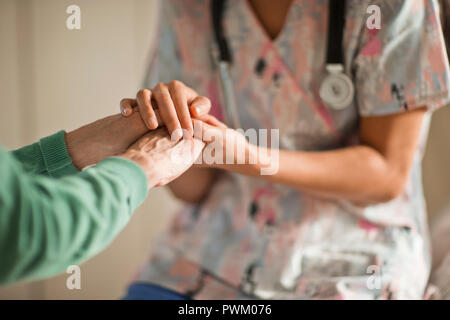 Jeune infirmière tenant les mains d'une femme senior. Banque D'Images