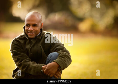 Smiling man sitting in a park. Banque D'Images