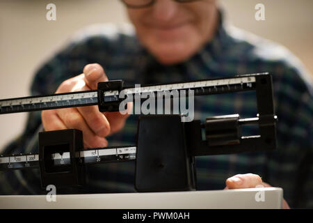 Man lui-même sur les balances de pesée dans le cabinet du médecin. Banque D'Images