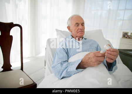 Senior man reading l'étiquette d'un flacon de médicaments. Banque D'Images