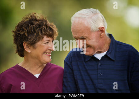 Infirmière mature et patient âgé souriant à l'autre. Banque D'Images