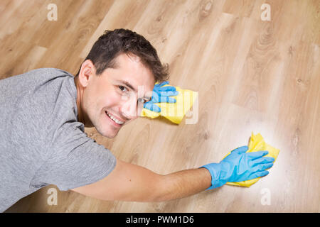 Service de nettoyage. Jeune homme nettoie avec chiffon jaune et bleu gants de protection dans l'appartement Banque D'Images