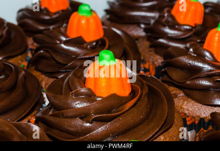 Muffins au chocolat noir avec des bonbons orange citrouille de glaçage. De délicieux petits gâteaux de tasse avec glaçage à la crème au beurre de tourbillons. Banque D'Images