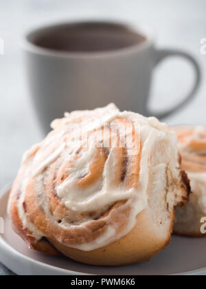 Brioches à la cannelle suédois Vegan Kanelbullar avec pumpkin spice,topping crème vegan cheese en plaque avec tasse de thé sur la table. Idée recette et pâtisseries - parfait à la cannelle.Copy space.Shallow DOF. La verticale Banque D'Images