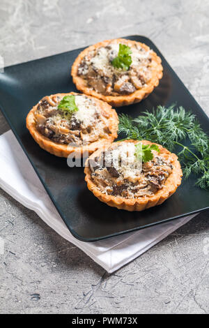 Des tartes salées automne champignons frais et de saison, dans une base de pâte croustillante sur fond gris Banque D'Images