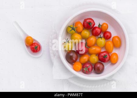 Divers différentes couleurs de tomates dans un bol en porcelaine et sur une cuillère (vu du dessus) Banque D'Images