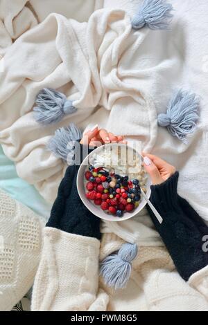 Femme est titulaire d'un bol de porridge et de fruits dans ses mains Banque D'Images