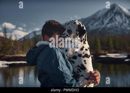 L'homme jouant avec son chien dalmatien en plein air près de lac de montagne. Banque D'Images