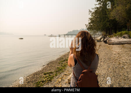 Une femme brune prend une photo de la brume entourant Vancouver de la 2018 Les incendies de forêt. Banque D'Images