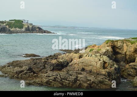 Bay avec les vagues se brisant sur ses rochers dans l'arrière-plan d'une maison cachée entre les pierres en Tapia de Casariego. La nature, voyage, loisirs. Le 2 août, Banque D'Images