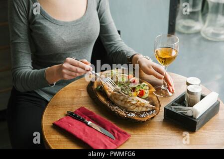 Femme mangeant des légumes grillés et du maquereau sur planche de bois Banque D'Images