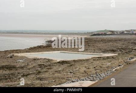 Piscine remplie par chaque marée sur la plage rocheuse à Westward Ho ! Dans le nord du Devon, Angleterre. Avec plage de sable et de la ville dans la distance. Banque D'Images