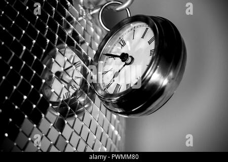 Close up arty shot d'une grande montre de poche en métal réveil à côté d'une boule disco argent en noir et blanc Banque D'Images
