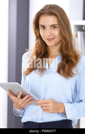 Jeune brunette business woman ressemble à une fille d'étudiant au travail dans bureau. Girl tout droit avec tablette PC. Banque D'Images