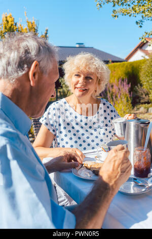 Heureux couple eating breakfast dans leur jardin en plein air Banque D'Images