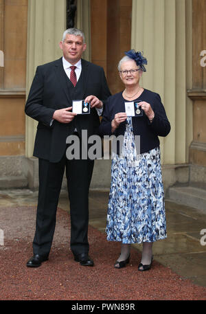 La CORRECTION DE LA FIN DE LÉGENDE RETRANSMIS À LA FIN DE SON MARI Stephen Adams et Margaret Guest holding Médailles de Bravoure Queen's après une cérémonie au Palais de Buckingham, à Londres. Banque D'Images