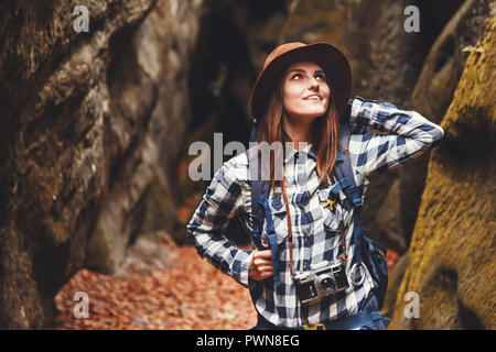 Billet jeune femme portant chapeau brun, chemise à carreaux, jeans et bottes marron avec sac à dos, admirant de canyon avec de la mousse sur les roches après la randonnée, les voyages concept Banque D'Images