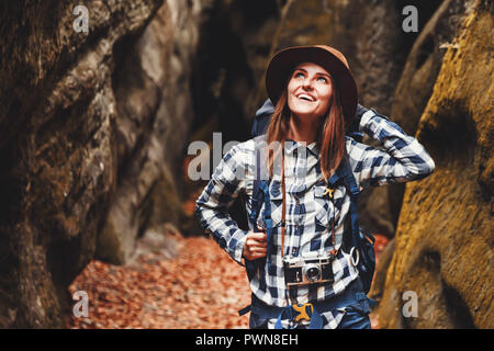 Billet jeune femme portant chapeau brun, chemise à carreaux, jeans et bottes marron sac à dos avec le sourire et d'admirer de canyon avec de la mousse sur les roches après la randonnée, les voyages concept Banque D'Images