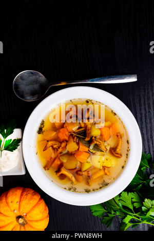 Tasse de soupe aux girolles, le potiron, la crème et les herbes, le persil, la feuille de laurier. Dof peu profondes. Vue de dessus Banque D'Images