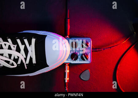 Close up of guitar player pied appuyé sur la pédale. Boucle d'effet de la musique musicien utilise la machine. Dans le quartier branché d'homme sneakers, son pied à jouer sur scène au cours d'hiver Banque D'Images