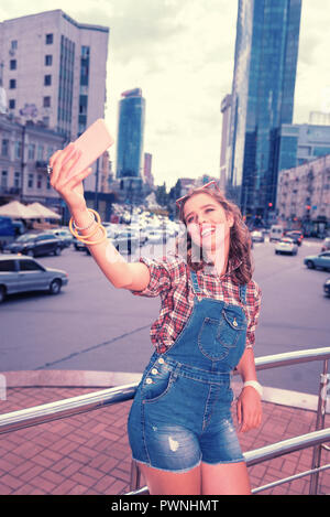 Transmission d'girl wearing Jumper en denim suit holding selfies téléphone faire rose Banque D'Images