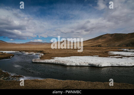 Paysage d'une nouvelle rivière dégelée commence à circuler dans la campagne mongole avec des montagnes au loin. Au printemps. Mongolie, arkhangaï Banque D'Images