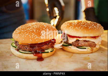 Deux burger fini sur une planche de bois. Cuisine ouverte dans la rue. Fast food Street Banque D'Images