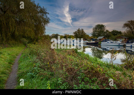 Lumière du soir l'atmosphère au-dessus de la rivière Nene, près de Peterborough à orton avec bateaux amarrés sur la rive et un sentier le long de la banque. Banque D'Images