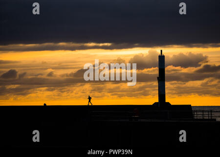 Aberystwyth, Pays de Galles, Royaume-Uni. 17 Oct, 2018. Pays de Galles Aberystwyth UK, le mercredi 17 octobre 2018. Météo France : un homme reprend sa course le long du mur du port au coucher du soleil à Aberystwyth, sur la côte ouest du pays de Galles Crédit photo : Keith morris/Alamy Live News Banque D'Images