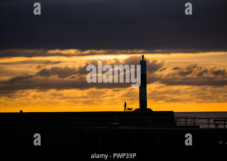 Aberystwyth, Pays de Galles, Royaume-Uni. 17 Oct, 2018. Météo France : le coucher du soleil à Aberystwyth Aberystwyth, Pays de Galles, Royaume-Uni mercredi 17 octobre 2018. Météo France : un homme promène son chien le long de la mur harboput à Aberystwyth, au coucher du soleil sur la côte ouest du pays de Galles Crédit photo : Keith morris/Alamy Live News Banque D'Images