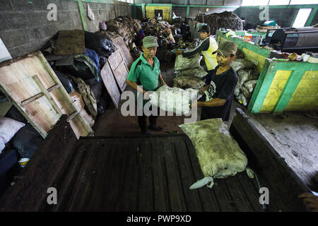 Bogor, Java ouest, Indonésie. 18 Oct, 2018. Deux travailleurs mis les bouteilles en plastique dans des sacs à charger le camion, pour être porté à l'éboueur. La banque gère des déchets déchets à base communautaire par la manipulation des déchets comme une ressource qui a une valeur écologique, d'éducation et de valeurs économiques, afin qu'il devienne un projet pilote pour la gestion des déchets des 3R : Adriana Crédit/Adinandra SOPA Images/ZUMA/Alamy Fil Live News Banque D'Images