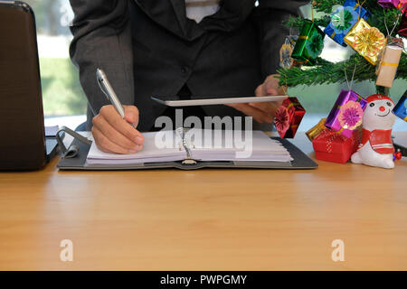 L'homme écrit reminder schedule Remarque sur portable. in l'organisation de planifier avec comprimé au lieu de travail social Banque D'Images