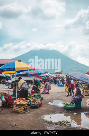 Les femmes et les jeunes filles en robe traditionnelles mayas vendre fruits sous les parasols en dehors d'un marché à Antigua, au Guatemala, à l'ombre d'un volcan Banque D'Images