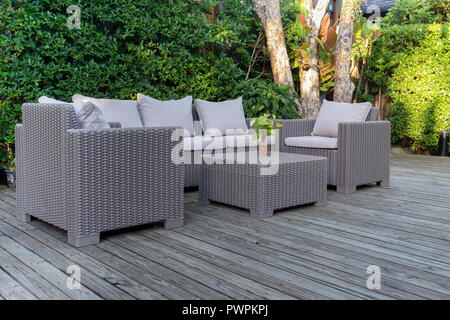 Grande terrasse patio avec meubles de jardin en rotin dans le jardin sur un plancher en bois. Banque D'Images