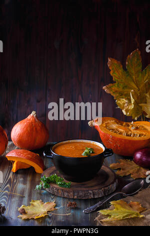 Soupe au potiron purée avec les verts dans une assiette sur une table. Sur l'arrière-plan de citrouilles et Menu restaurant concept Copy space Banque D'Images