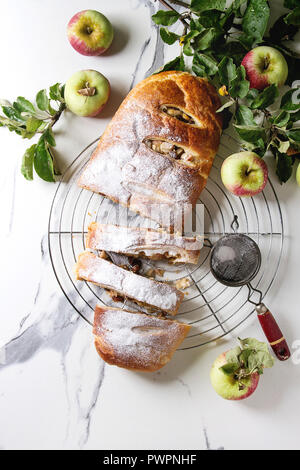 Des tranches de pâte feuilletée strudel aux pommes Tarte sur grille de refroidissement servi avec des pommes mûres, branches, cieve et le sucre en poudre sur le marbre blanc textur Banque D'Images