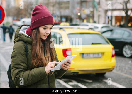Belle fille de tourisme avec une tablette dans une rue de Prague appelle un taxi ou regarde une carte ou utilise l'Internet ou une application mobile. Le voyage ou le tourisme. Banque D'Images