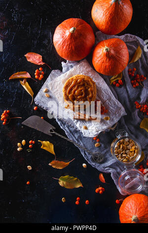 Concept d'automne. Crêpes à la citrouille avec garniture au caramel, avec des citrouilles, des feuilles sur un fond sombre. Vue d'en haut Banque D'Images