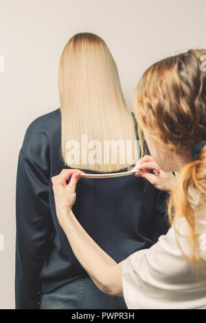 Coiffure peignes ses clients de longs cheveux blonds en salon de coiffure, un contrôle de la ligne de coupe Banque D'Images