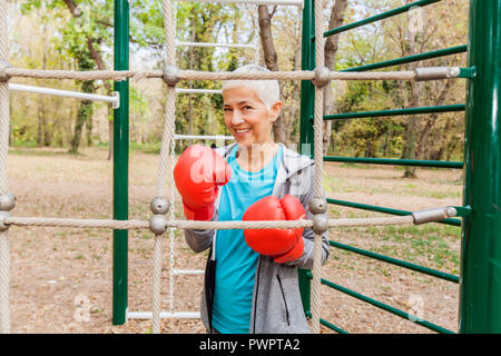 Portrait Of Happy Fit Woman avec gant de boxe au sport en plein air dans les vêtements de sport. Les personnes âgées actives de vie de forme physique Banque D'Images